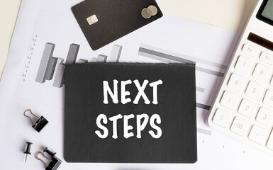 Next steps text on black paper over business graphs with credit card, calculator and office accessories
