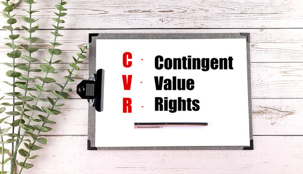 CVR abbreviation for contingent value rights written on white clipboard with pen and eucalyptus on wooden table