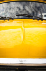 Vintage Yellow Compact Car – Hood Detail
Detailed close-up of the hood of a vintage yellow compact car, showing smooth curves and polished paintwork that highlight retro elegance.