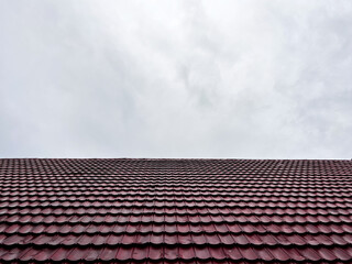 Stunning burgundy roof tiles shimmering under a cloudy sky, offering durable protection and stylish design for modern home exteriors, construction projects
