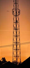 Silhouetted cellular tower against sunsets vibrant backdrop