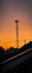 Silhouette of communication tower against orange sky