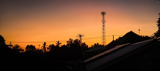 Sunset silhouettes antenna and rooftops
