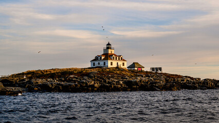 Egg Rock lighthouse is seen from water under sunset	