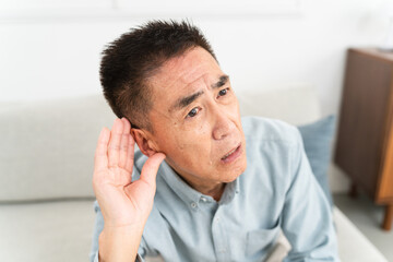 耳に手を当てて聞きかえす熟年男性