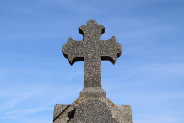 Old stone cross in the cemetery with an Irish sign. God and life after life. Cross in a cemetery with a blue sky.	
