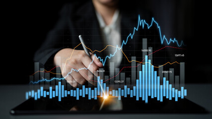 A business professional examines stock market data displayed on a tablet, featuring various graphs...