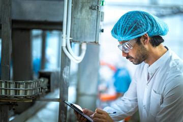A Quality Assurance (QA) specialist audits a smart factory. He is thoughtfully monitoring an AI driven automated canning line for hygiene and system compliance.