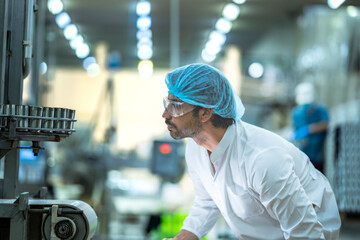 A Quality Assurance (QA) specialist audits a smart factory. He is thoughtfully monitoring an AI driven automated canning line for hygiene and system compliance.