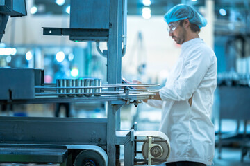 A Quality Assurance (QA) specialist in PPE audits a smart factory. He is monitoring an AI-driven automated line, checking system data on his clipboard.