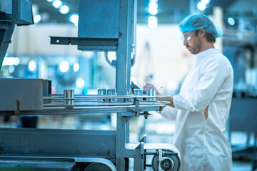 A Quality Assurance (QA) specialist in PPE audits a smart factory. He is monitoring an AI-driven automated line, checking system data on his clipboard.