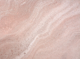 Pink marble, a close-up of the wavy pattern of natural stone with inclusions.