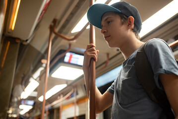 smiling 12 year old boy with backpack in train carriage, subway, metro	