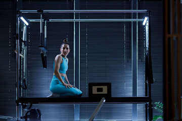 Workout session on reformer pilates machines in an elegant studio with dim lighting and modern...