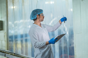 A Quality Assurance QA specialist in PPE audits a smart factory. He monitors the food safety and...