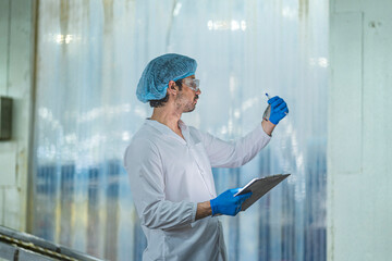 A Quality Assurance QA specialist in PPE audits a smart factory. He monitors the food safety and...