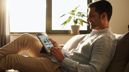 Man reclining on couch using digital tablet with sale advertisement in daylight