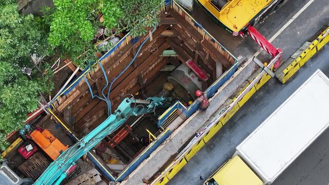 View from above Some workers do pipeline repair work with complete safety equipment. a large pipeline network and also an underground cable network can be seen
