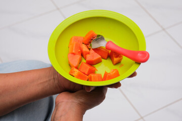 Person hand holding a plate with fresh sliced ​​papaya fruit