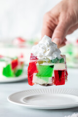 A hand serving a slice of a homemade colourful jelly dessert.