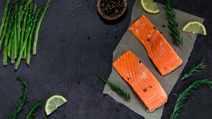 Top down view of fresh raw salmon fillets with herbs, lemon and asparagus.
