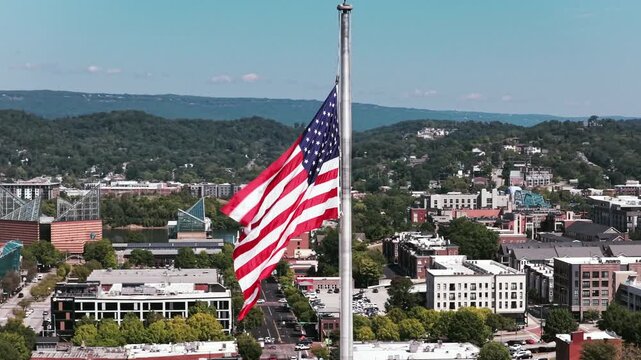 Close aerial shot of an American flag flying over downtown Chattanooga, with the Tennessee Aquarium visible in the background.