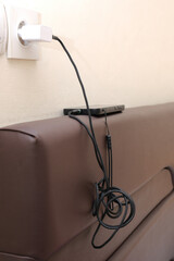 A Mobile phone on the bed headboard is being charged