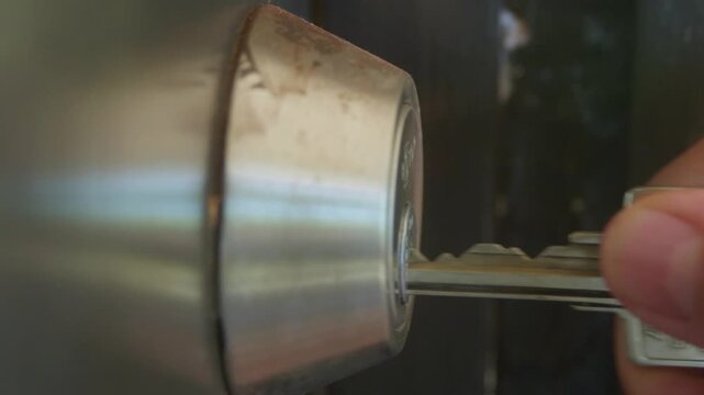 Manipulating a front door deadbolt with the key; locking and unlocking, close up shot.