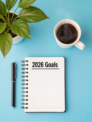 Notebook with 2026 goals, pen, coffee, and plant