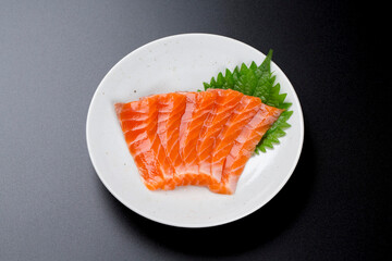 皿に盛られたサーモンのお刺身 黒背景