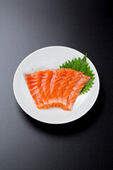 皿に盛られたサーモンのお刺身 黒背景