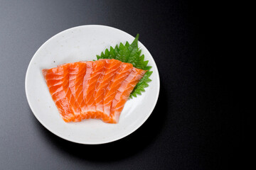 皿に盛られたサーモンのお刺身 黒背景