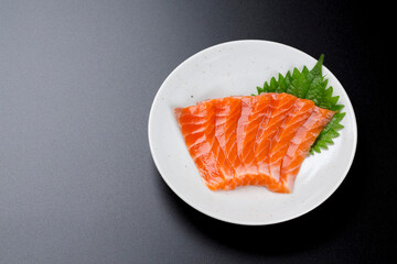 皿に盛られたサーモンのお刺身 黒背景