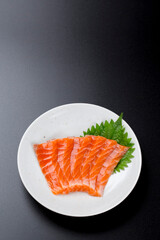 皿に盛られたサーモンのお刺身 黒背景