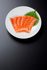 皿に盛られたサーモンのお刺身 黒背景