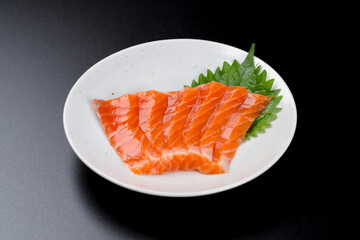 皿に盛られたサーモンのお刺身 黒背景