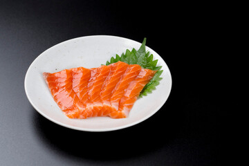 皿に盛られたサーモンのお刺身 黒背景