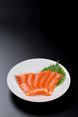 皿に盛られたサーモンのお刺身 黒背景