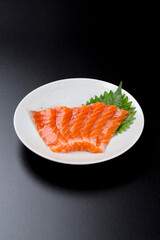 皿に盛られたサーモンのお刺身 黒背景