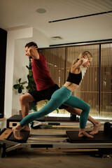 Couple practicing Pilates together in a modern studio with natural light in the morning