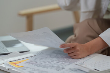 Paperwork Chaos. Close-up of woman holding tax documents while sitting at a desk.