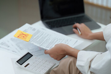 Tax Preparation. Individual reviewing tax documents with calculator and laptop.