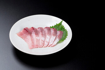 皿に盛られたブリのお刺身 黒背景