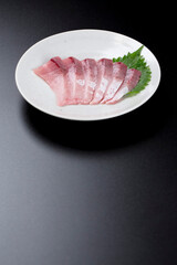 皿に盛られたブリのお刺身 黒背景