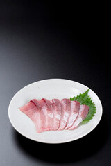 皿に盛られたブリのお刺身 黒背景