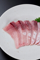 皿に盛られたブリのお刺身 黒背景