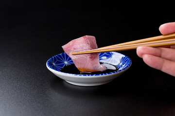 皿に盛られたブリのお刺身 黒背景