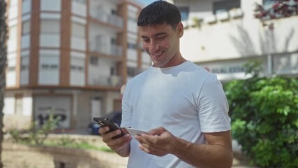 Man holding smartphone and creditcard near building facade on sunny street; digital payment convenience joy. - Powered by Adobe