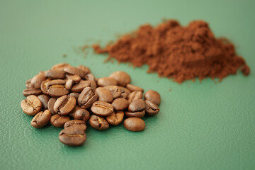Coffee beans and ground coffee on green surface