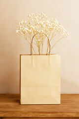 Brown paper shopping bag with handles on a wooden background ready for your retail or gift packaging design